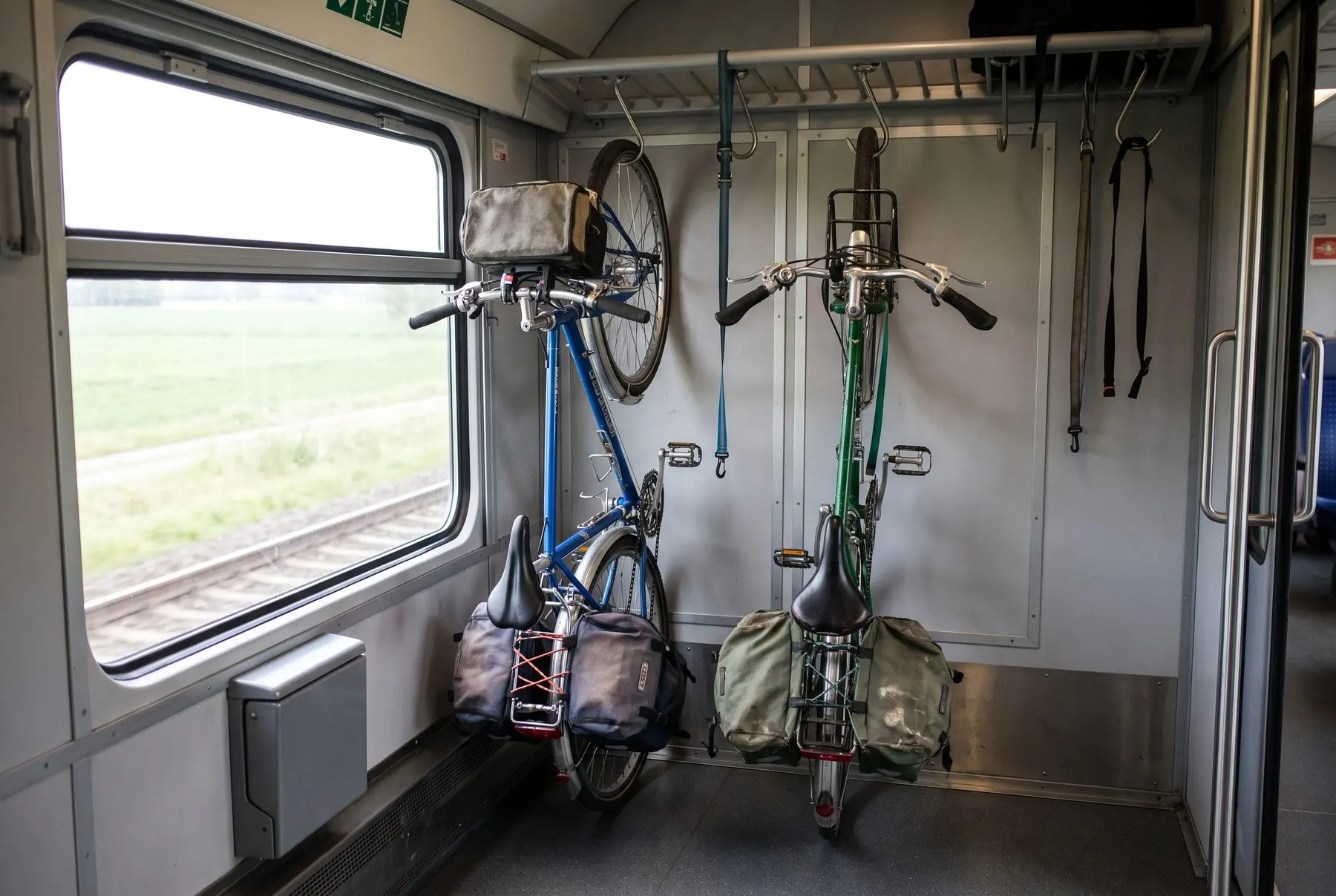 A touring bicycle standing in a dedicated bike carriage next to a train window