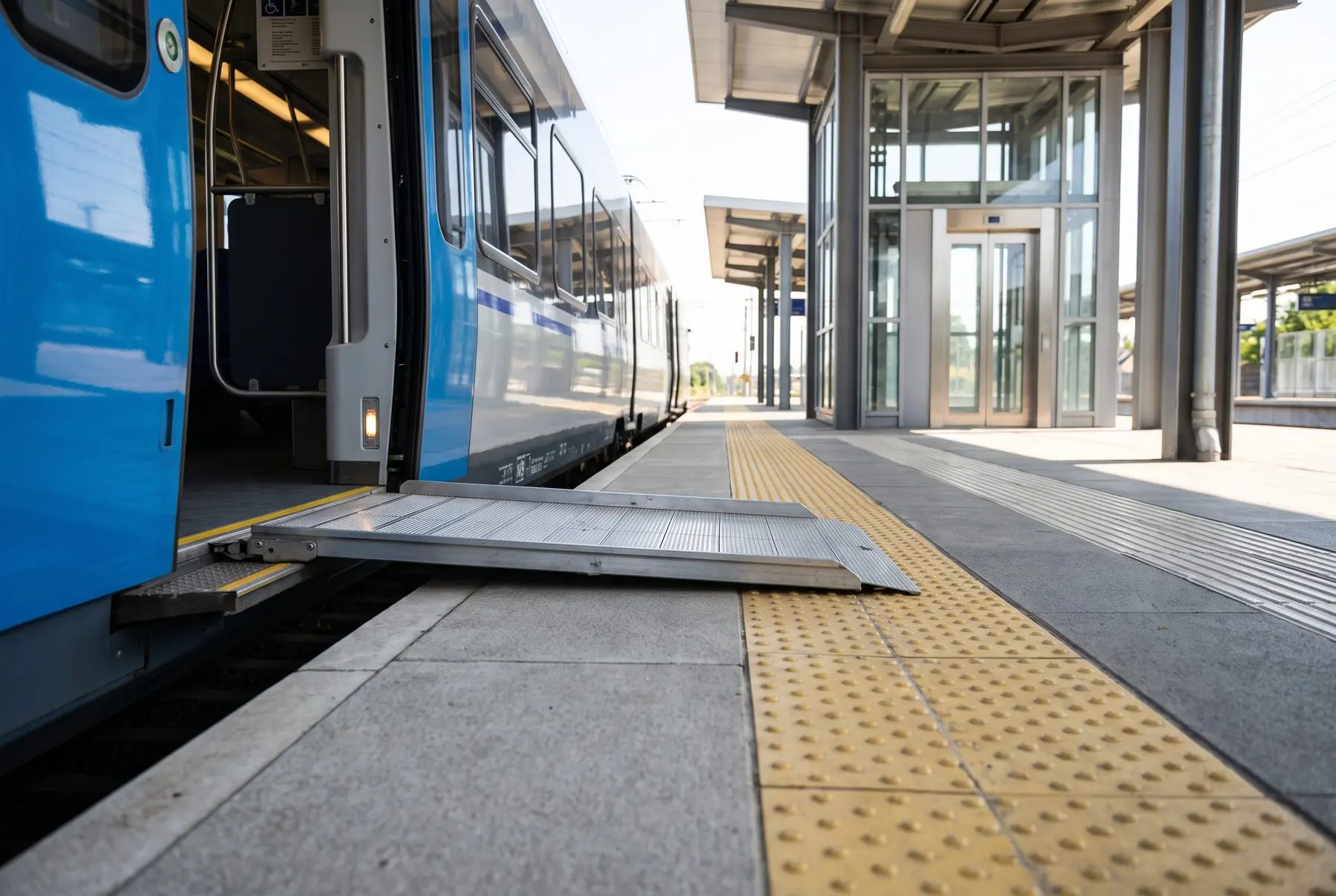 A wheelchair user rolling along a level ramp toward a train platform